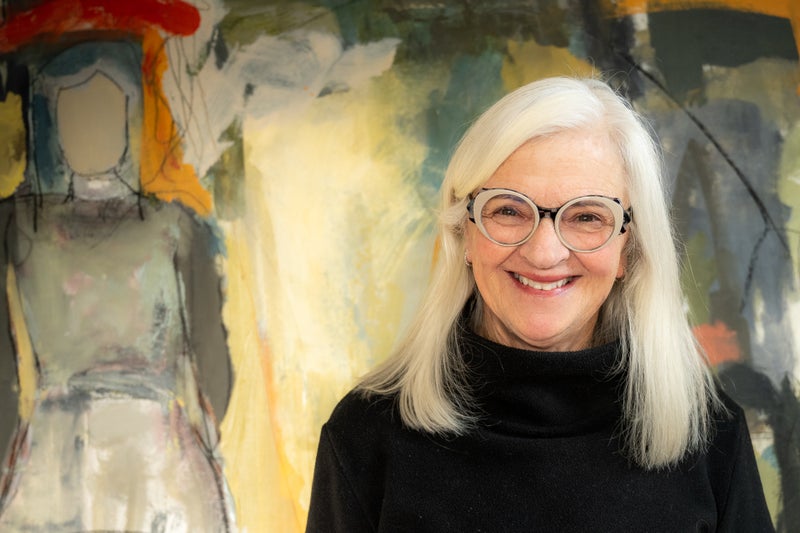 Artist Ginny Snowdon Trousdale stands in front of their artwork